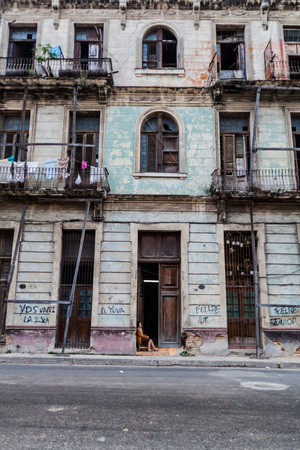 HAVANA, CUBA - FEB 22, 2016: Old woman sits in the entrance to a dilipitated building in Havana.のeditorial素材