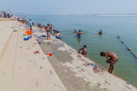 VARANASI, INDIA - OCTOBER 25, 2016: Local people wash themself in sacred water of Ganges rover at a Ghat (riverfront steps) in Varanasi, Indiaのeditorial素材