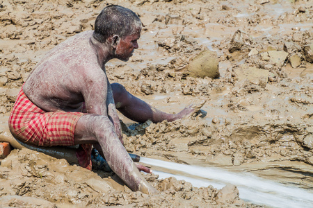 VARANASI, INDIA - OCTOBER 25, 2016: Local man cleans mud sediments at Ghats (riverfront steps) left after monsoon period flooding in Varanasi, Indiaのeditorial素材