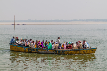 VARANASI, INDIA - OCTOBER 25, 2016: Small boat carrying local people near Ghats (riverfront steps)...