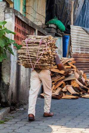 SANTIAGO ATITLAN, GUATEMALA - MARCH 24, 2016: Local indigenous man with a load of firewood in Santiago Atitlan village.のeditorial素材