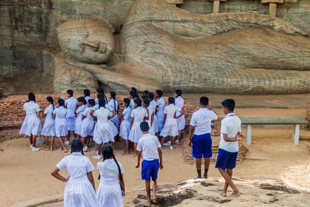 POLONNARUWA, SRI LANKA - JULY 22, 2016: Children in school uniforms visit reclining Buddha statue at Gal Vihara rock temple in the ancient city Polonnaruwa, Sri Lankaのeditorial素材