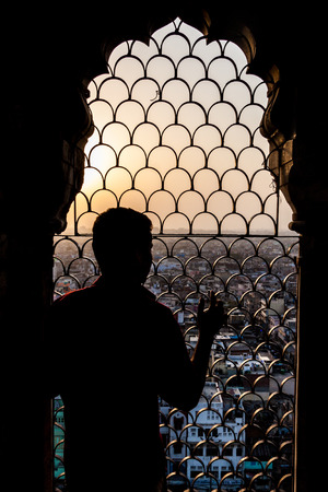 Man watches a sunset from Jama Masjid mosque in the center of Delhi, India.の写真素材