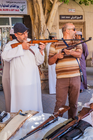 NIZWA, OMAN - MARCH 3, 2017: Customers of a rifle seller trying his guns at the Souq in Nizwa, Omanのeditorial素材