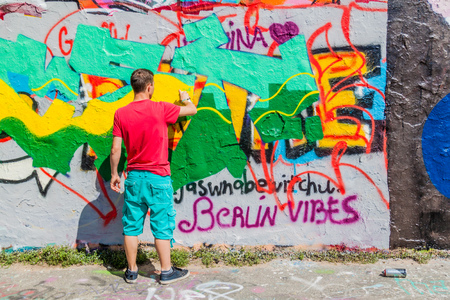 BERLIN, GERMANY - AUGUST 6, 2017: Graffiti artist painting on a section of Berlin wall in Mauerpark.のeditorial素材
