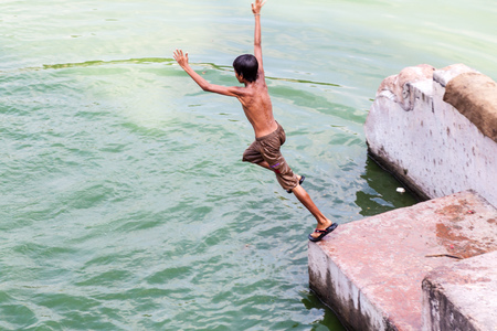 PUTHIA, BANGLADESH - NOVEMBER 10, 2016: Local boy jumps into Gopal Chowki pond in Puthia village, Bangladeshのeditorial素材
