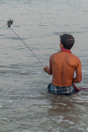 DUBLAR CHAR, BANGLADESH - NOVEMBER 14, 2016: Hindu devotee taking selfie during his holy dip during Rash Mela festival at Dublar Char (Dubla island), Bangladesh.のeditorial素材