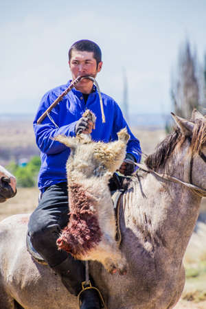 ISSYK KUL, KYRGYZSTAN - JULY 15, 2018: Player of kok boru, traditional horse game, with a goat carcass at the Ethnofestival Teskey Jeek at the coast of Issyk Kul lake in Kyrgyzstanのeditorial素材