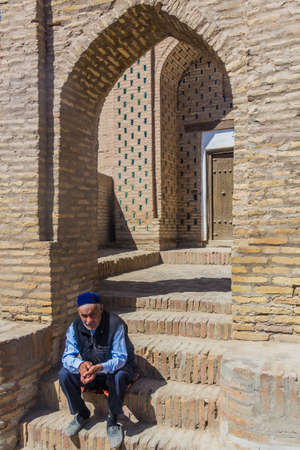 KHIVA, UZBEKISTAN - APRIL 26, 2018: Local man sitting in a gate in the old town of Khiva, Uzbekistan.のeditorial素材
