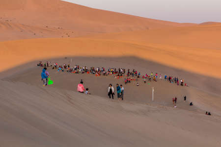 DUNHUANG, CHINA - AUGUST 21, 2018: Tourists observe sunrise at Singing Sands Dune near Dunhuang, Gansu Province, Chinaのeditorial素材