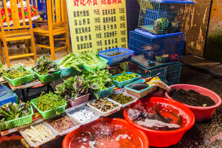 FENGHUANG, CHINA - AUGUST 14, 2018: Various food items in front of a restaurant in Fenghuang Ancient Town, Hunan province, Chinaのeditorial素材