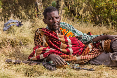 SIMIEN MOUNTAINS, ETHIOPIA - MARCH 16, 2019: Armed scout guarding tourists in Simien mountains,...