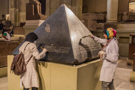 CAIRO, EGYPT - JANUARY 27, 2019: Employees cleaning a pyramidion in the Egyptian Museum in Cairo,...