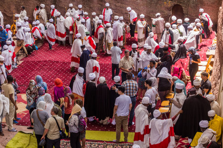 LALIBELA, ETHIOPIA - MARCH 29, 2019: Christian priests, devotees and tourists in front of Bet...