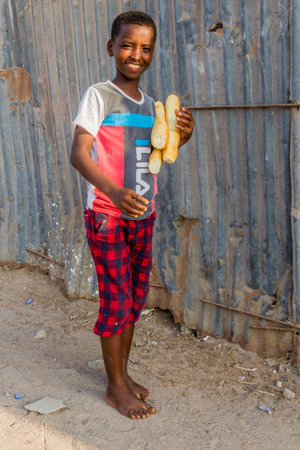 TADJOURA, DJIBOUTI - APRIL 19, 2019: Local boy with baguettes in Tadjoura, Djiboutiのeditorial素材