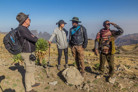 SIMIEN MOUNTAINS, ETHIOPIA - MARCH 17, 2019: Tourists, local tour guide and an armed scout guarding...