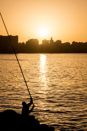 Silhouette of a fisherman and a skyline of Alexandria, Egyptの写真素材