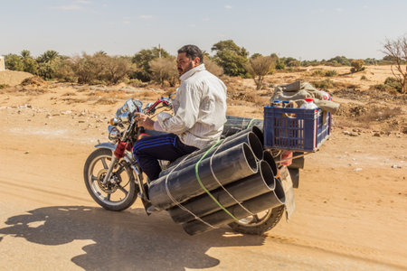 DAKHLA, EGYPT - FEBRUARY 8, 2019: Motorbike carrying thick pipes in Al Qasr village in Dakhla oasis, Egyptのeditorial素材