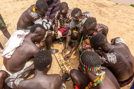 KORCHO, ETHIOPIA - FEBRUARY 4, 2020: Men of Karo tribe playing mancala (bao) game in Korcho village,...