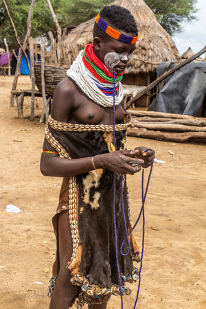 KORCHO, ETHIOPIA - FEBRUARY 4, 2020: Karo tribal girl making bead necklace in her Korcho village,...