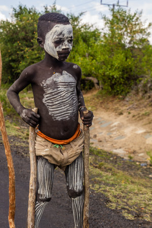 OMO VALLEY, ETHIOPIA - FEBRUARY 5, 2020: Banna tribe boy walking on stilts, Ethiopiaのeditorial素材