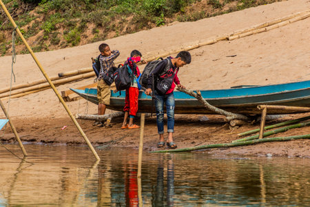 NAM OU, LAOS - NOVEMBER 24, 2019: Boys with a boat at Nam Ou river in Luang Prabang province, Laosのeditorial素材