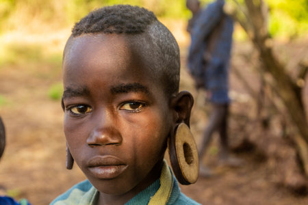 OMO VALLEY, ETHIOPIA - FEBRUARY 6, 2020: Mursi tribe girl in her village, Ethiopia