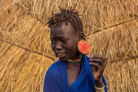 OMO VALLEY, ETHIOPIA - FEBRUARY 6, 2020: Mursi tribal girl in her village, Ethiopia