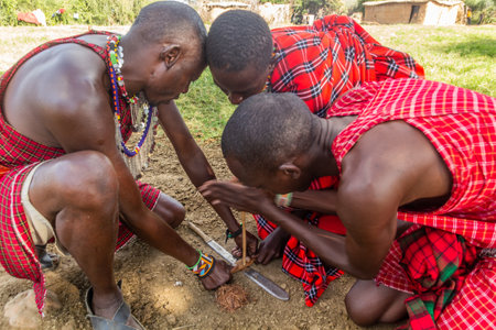 MASAI MARA, KENYA - FEBRUARY 20, 2020: Masai men making a fire in their village, Kenyaのeditorial素材