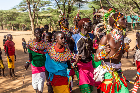 SOUTH HORR, KENYA - FEBRUARY 12, 2020: Group of Samburu tribe young men and women dancing wearing colorful headpieces made of ostrich feathers after malecircumcision ceremony.のeditorial素材