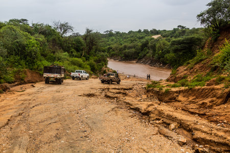 OMO VALLEY, ETHIOPIA - FEBRUARY 4, 2020: Vehicles waiting in front of a ford through Kizo river, Ethiopiaのeditorial素材