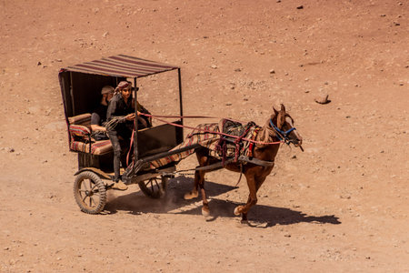 PETRA, JORDAN - JULY 11, 2022: Tourists ride a charriot in the ancient city Petra, Jordanのeditorial素材