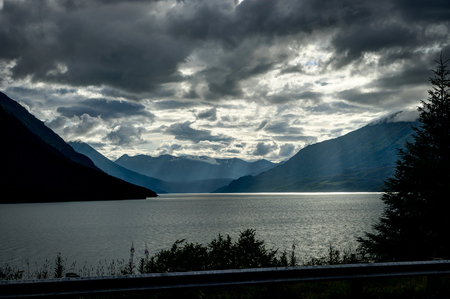 God rays with clouds and trees in foreground in Alaska.の写真素材