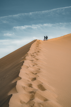 Sand dunes under blue sky. Sahara Desert, Previously, village houses transferred due to sands movement.の写真素材