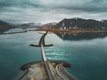 Aerial view of road 1 in iceland with bridge over the sea in Snaefellsnes peninsula with clouds, water and mountain in backgroundの写真素材