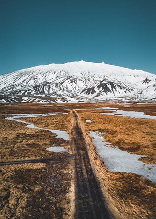 Aerial drone photo of a empty quit road road towards a huge volcanic mountain Snaefellsjokull in the distance, near Snaefellsjokull national park, Iceland.の写真素材