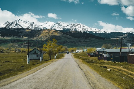 Village in Kazakhstan with Tian Shan mountains in background and small street in foreground, Kazakhstan Central Asiaの写真素材