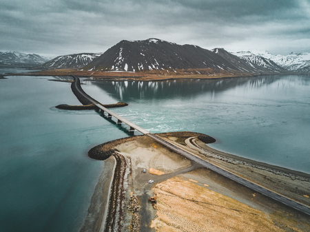 Aerial view of road 1 in iceland with bridge over the sea in Snaefellsnes peninsula with clouds, water and mountain in backgroundの写真素材