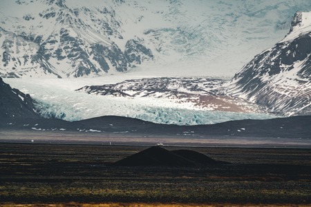 Road leading towards huge glacier and mountains in Iceland Vatnajokull glacier aerial drone image with street highway and clouds and blue sky. Dramatic winter scene of Vatnajokull National Park, Iceland, Europe. Beauty of nature concept background.の写真素材