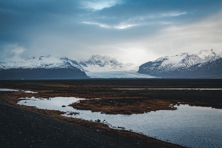 Road leading towards huge glacier and mountains in Iceland Vatnajokull glacier aerial drone image with street highway and clouds and blue sky. Dramatic winter scene of Vatnajokull National Park, Iceland, Europe. Beauty of nature concept background.の写真素材