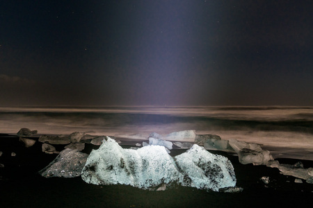 Night stars Ice rock with black sand beach at Jokulsarlon beach (Diamond beach) in southeast Icelandの写真素材