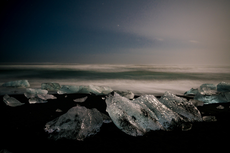 Night stars Ice rock with black sand beach at Jokulsarlon beach (Diamond beach) in southeast Icelandの写真素材