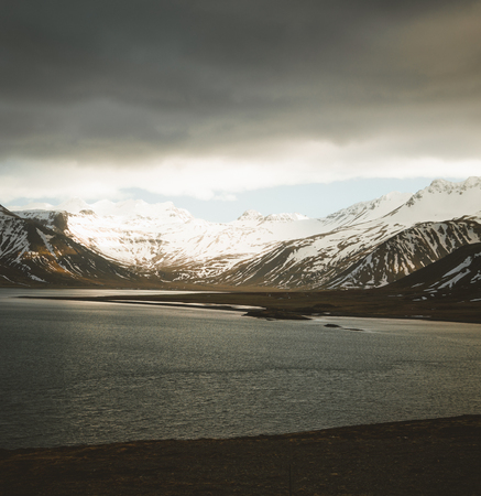 Iceland dramatic sky with snow capped mountain at ocean lake water. Southern side if the country.の写真素材
