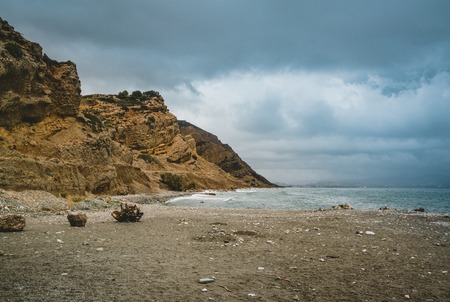 Typical beach scene in island crete. View towards ocean. With Mountains in background on a cloudy day.の写真素材