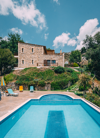 Mesonisia, Rethymno, Crete - August 2018: View towards villa Krios with swimming pool on a sunny day with blur sky. Krios Villa is a resort located in Mesonisia village in Rethymno,Crete.のeditorial素材