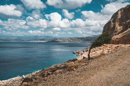 Panoramic view of rocks and beach with sky and clouds in Crete, Greece. Amazing scenery with crystal clear water and the rock formation against a deep blue sky during Summer period. Greece, Europeの写真素材