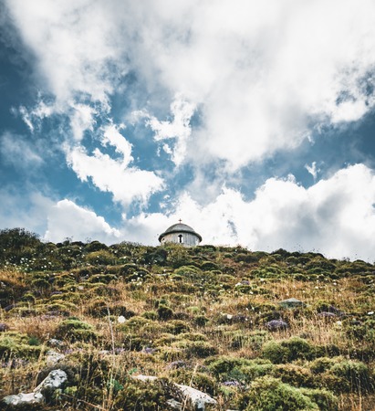 Crete, Greece, small unfinished church, amazing chapel abandoned in the mountains stones and rocks with blue sky, sunny and clouds. tourist point of interest, attractionの写真素材