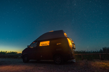 LITHUANIA - August 2018: VW Transporter T4 during the night on a campground in Latvia with light inside. View towards sky and stars in the background. The Volkswagen Transporter (T4) is a van produced by the German manufacturer Volkswagen Commercial Vehicのeditorial素材