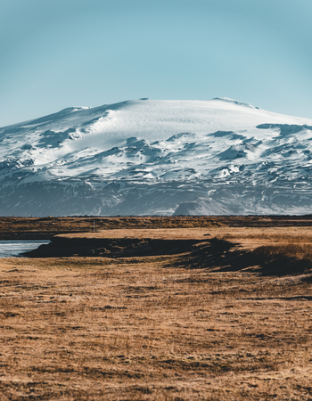 Iceland typical mountain winter scene with grass in foreground and massive mountain in background.の写真素材