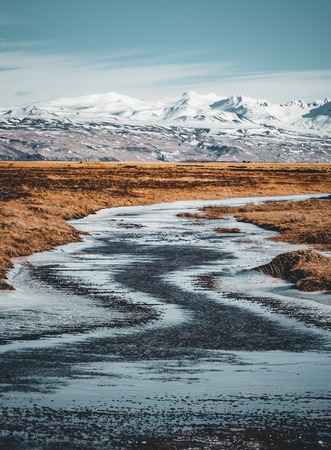 Iceland typical mountain winter scene with grass in foreground and massive mountain in background.